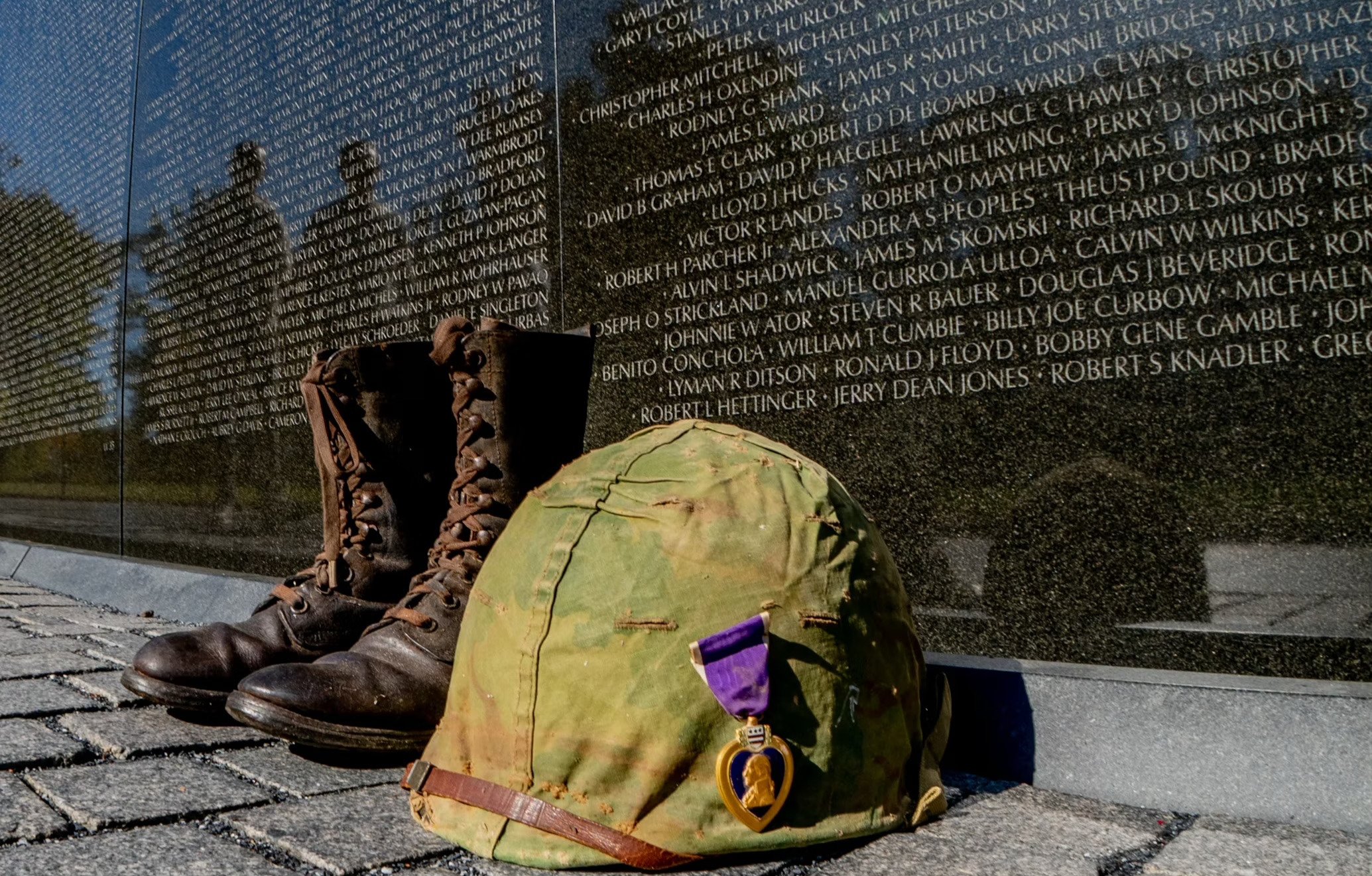 Military helmet and boots placed at the Vietnam Veterans Memorial Wall in Washington D.C., a tribute to fallen soldiers